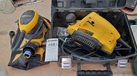 Image of DeWalt DW680K hand planer with attached dust bag, power cord, placed on top of carrying case