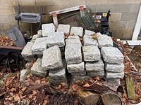 Front view of stacked granite paving stones against cinderblock wall