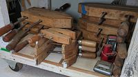 Multiple wooden parallel clamps stacked on shelf.
