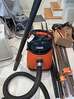 Front view of vacuum, corrugated hose attached, straight tube laid out, coiled power cord on top