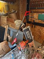 Toro Power Shovel and Husqvarna chainsaw placed against workshop wall among boxes and netting.