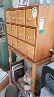Front view of wooden chest showing 12 square drawers with metal knobs.
