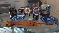 Overview of Blue Willow plates and bowl, parasol, vase, and tin on glass table
