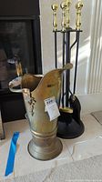 Full fireplace set showing brass bucket and black metal stand with fireplace tools.