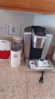 Full view of corner kitchen counter with Keurig coffee maker, Gevalia canister, Ice-O-Mat, and coffee grinder