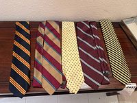 9 neckties laid out on a table, showing colors and stripe/polka dot patterns