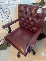 Front view showing tufted burgundy leather backrest and padded leather seat with nailed trim on armrests.