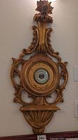 Full view of large vintage barometer with ornate golden carved wooden frame mounted on wall.