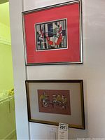 Two framed and matted wall art pieces hanging on a wall, showing overall lot contents.