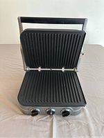 Open view of the electric griddler showing ribbed non-stick grill plates and three control knobs on the front.