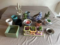 Full group view of various decorative plates, bowls, planters, and figurines on a grey surface.