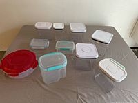 Various sizes and shapes of plastic food containers with lids on table, showing diverse collection.