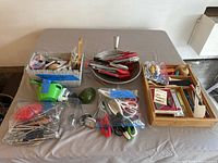 Overview of the entire collection showing different kitchen gadgets laid out including tongs, scissors, plastic and metal utensils, and other tools.