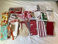 Group of towels and aprons showing various colors, patterns and wear levels on a bed surface.