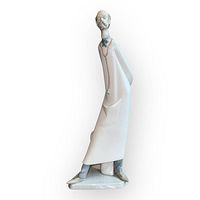 Front view of the Lladro doctor figurine showing the tall slender figure in a long white coat with blue bow tie and grey shoes, standing with a slight forward lean.
