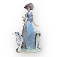 Front view showing the full figurine with woman in pastel dress and two detailed dogs standing on base.
