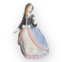 Front view of glossy porcelain figurine of a girl in traditional dress holding parasol handle, showing detailed facial features and skirt patterns.