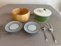 Overview of salad spinner, wooden bowl, plates and serving utensils