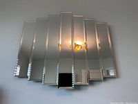 Full view of the segmented wall mirror with seven beveled vertical panels showing reflective surfaces.