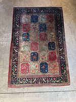 Full view of the small rectangular rug showing the overall floral block pattern and bird border.