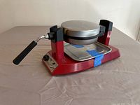 Red Waring Pro waffle maker closed with handle and base visible