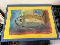 Full front view of framed painting showing fish motif, yellow mat, blue frame