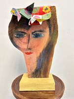 Front view of the wooden carved lifesize lady head sculpture with painted face and colorful floral metal crown.