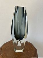 Front view of smoke grey facetted Sommerso vase on wooden stool.