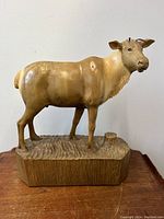 Front view of moose wooden carving sculpture on textured wooden base.