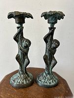 Front view of the pair of bronzed metal monkey candleholders showing monkeys climbing the vine stems under the floral candle cups.