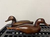 Pair of carved wooden duck decoys shown side by side from the side view, displaying shape and finish.