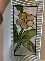 Close-up view showing pink flower petal and green leaves with textured clear background glass.