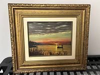 Frontal image of the gilt framed oil painting on board showing sunset fishing boat scene signed F Harvey