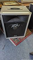Front view of Peavey 112 speaker cabinet showing grille, Peavey logo, horn, and speaker cone.