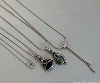 Four vintage 925 silver necklaces laid out, showing pendants and chains.