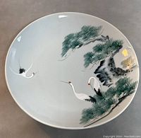 Overview of the round porcelain platter with three hand painted cranes and pine tree.