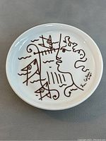Front view of ceramic plate with Jean Cocteau line drawing and signature.