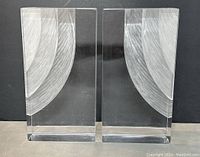 Front view of matched pair of clear Lucite bookends with etched curved designs.
