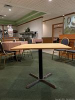 Front view of assembled table showing square particle board tabletop and central metal pedestal base
