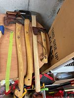 Three Gransfors Bruks axes and hatchets laid side by side on a wood bench