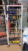 Full view of white metal clamp rack on wheels loaded with various clamps, bolt cutters, and crowbar