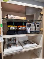Overview photo showing Kirkland t-shirt packs, base layers, heating pad, and white vests stacked in cabinet