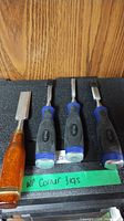 Four chisels and plastic case on shelf