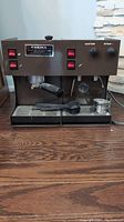Front view of espresso machine showing housing, control switches, drip tray, portafilter and baskets