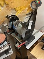 Full view of bench grinder on stand with lamp and wheels