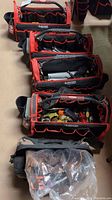 Four red and black Husky open-top tool bags lined up with tools visible in pockets