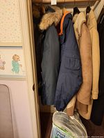 Four men's winter jackets hanging in a closet showing variety of styles and colors.