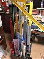Bin holding assorted levels, rulers, t-squares and gauges