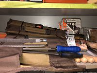 Canvas tool roll unrolled showing five rasps/files with wooden and plastic handles on shelf