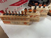 All three CMT router bit sets displayed on wooden storage blocks with original packaging in the background.